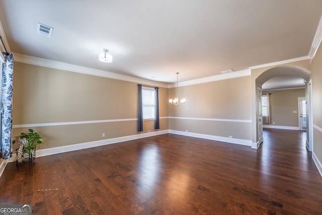 empty room featuring dark wood-style floors, baseboards, visible vents, and arched walkways