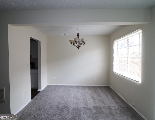 empty room with dark colored carpet, visible vents, baseboards, and an inviting chandelier