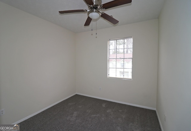 spare room with dark carpet, a ceiling fan, and baseboards