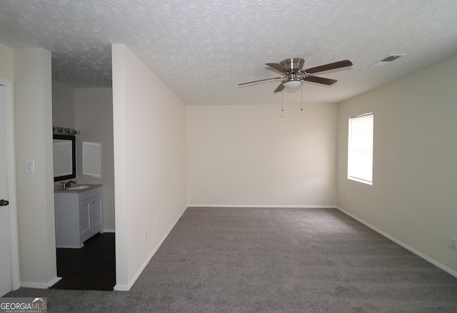 carpeted spare room featuring visible vents, a ceiling fan, a sink, a textured ceiling, and baseboards