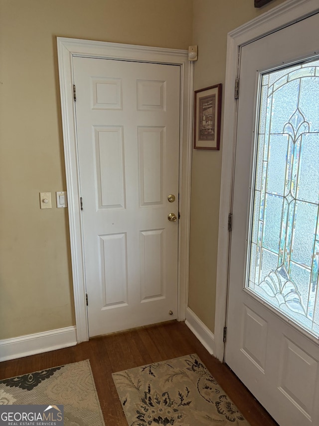 doorway with dark wood-style floors and baseboards