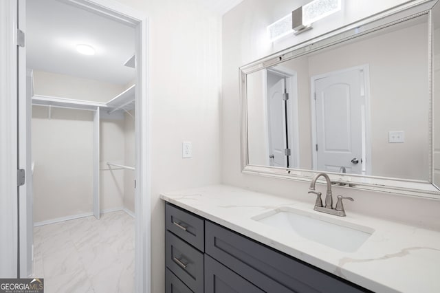 bathroom featuring marble finish floor, a walk in closet, and vanity