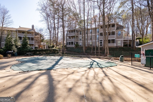 community pool with a patio area and fence