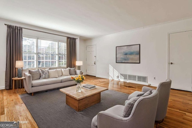 living room with visible vents, crown molding, baseboards, and wood finished floors