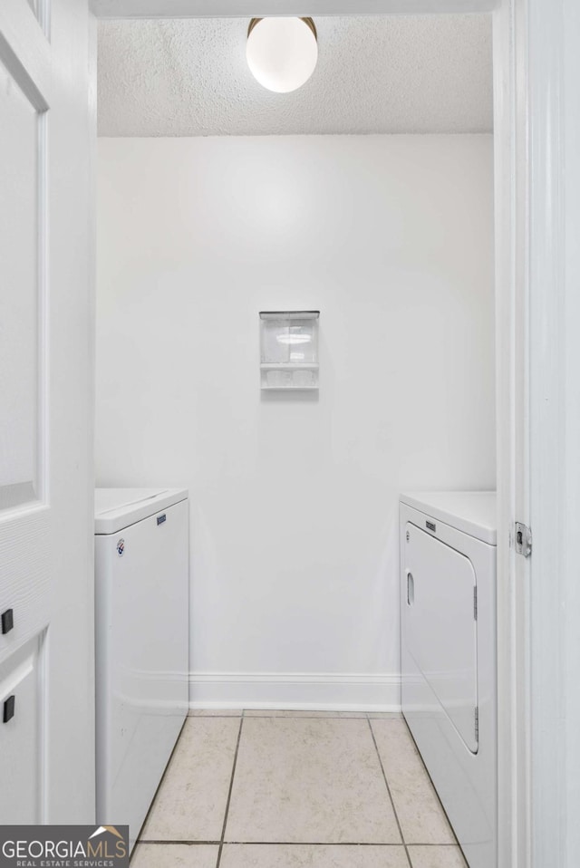 laundry room with washer and dryer, laundry area, light tile patterned flooring, and a textured ceiling