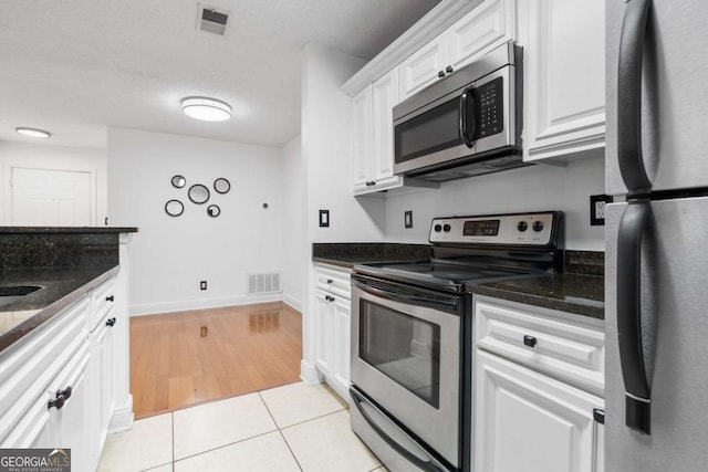 kitchen with appliances with stainless steel finishes, light tile patterned floors, visible vents, and white cabinetry