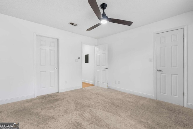 unfurnished bedroom with a textured ceiling, ceiling fan, carpet floors, visible vents, and baseboards