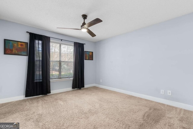 empty room featuring ceiling fan, a textured ceiling, baseboards, and carpet flooring