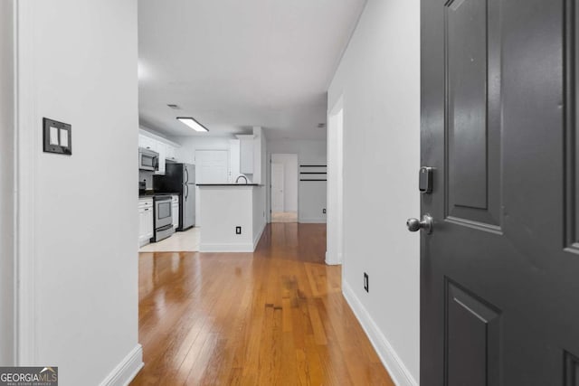 hallway featuring light wood-type flooring, visible vents, and baseboards