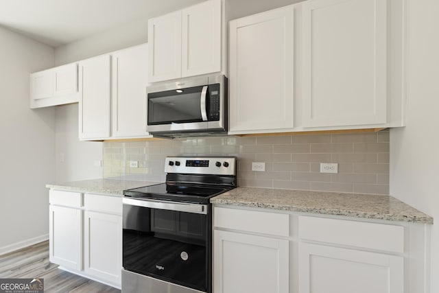 kitchen featuring stainless steel appliances, backsplash, light wood-style floors, and white cabinetry