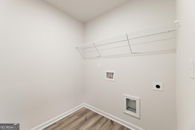 clothes washing area featuring electric dryer hookup, light wood-type flooring, washer hookup, and baseboards