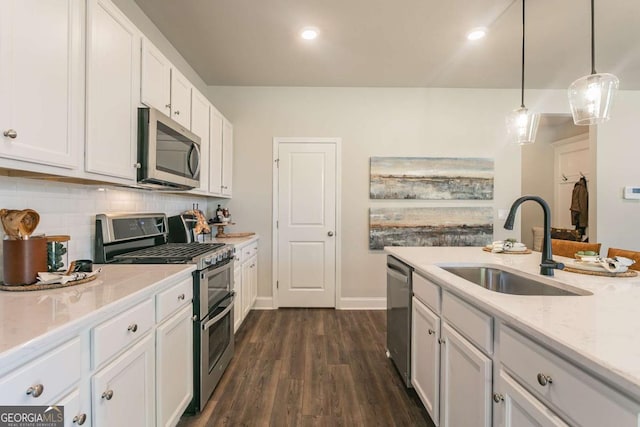 kitchen featuring white cabinets, dark wood-style floors, a sink, stainless steel appliances, and backsplash