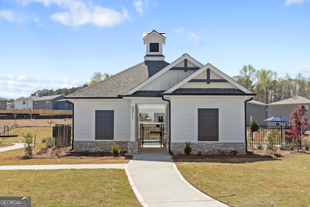 view of front facade featuring stone siding, a gate, and roof with shingles