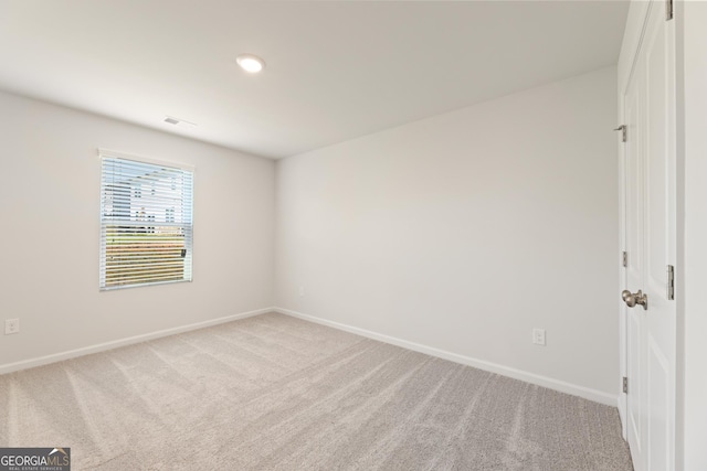 spare room with light carpet and baseboards