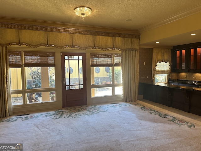 interior space with a textured ceiling, ornamental molding, and carpet flooring