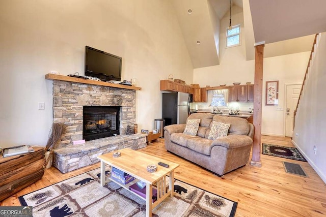 living area featuring light wood-style flooring, a fireplace, visible vents, and a wealth of natural light