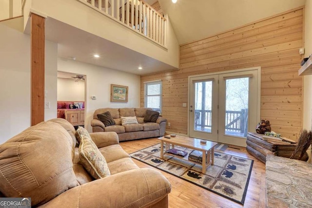 living area with a healthy amount of sunlight, wooden walls, wood finished floors, and a towering ceiling