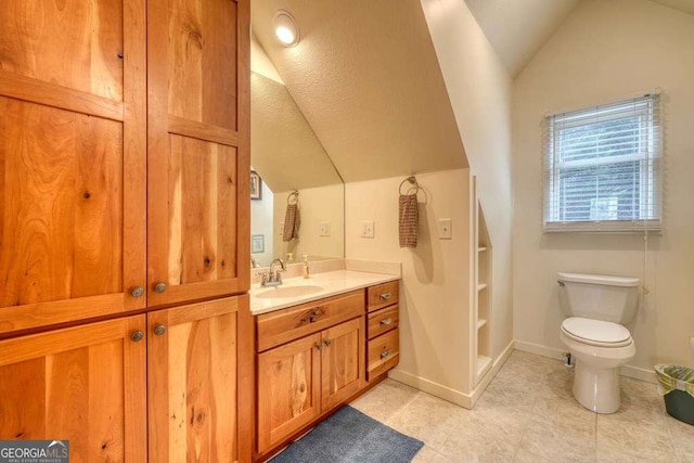 bathroom with vaulted ceiling, toilet, vanity, and baseboards