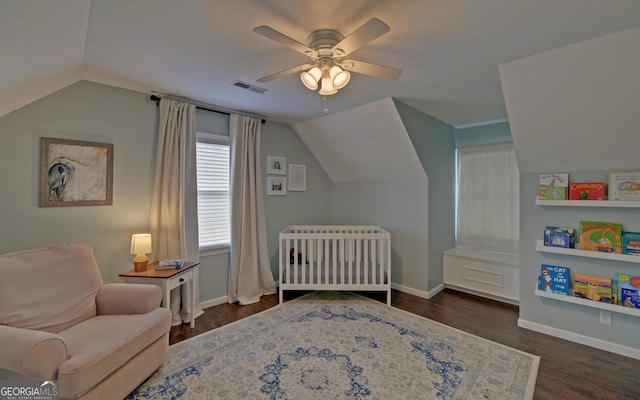 bedroom with lofted ceiling, visible vents, dark wood-type flooring, a nursery area, and baseboards