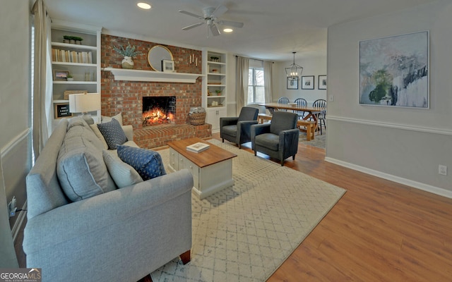 living area with built in shelves, recessed lighting, wood finished floors, baseboards, and a brick fireplace