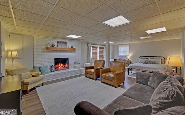 living room featuring a paneled ceiling, a fireplace, and wood finished floors