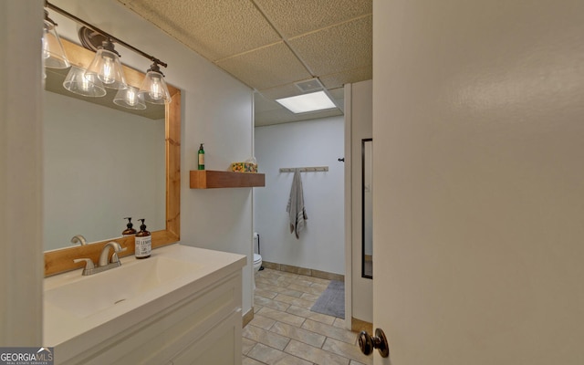 full bathroom with visible vents, toilet, vanity, a drop ceiling, and baseboards