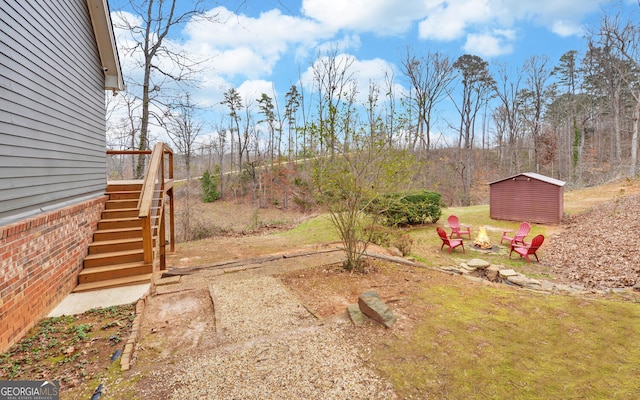 view of yard featuring an outbuilding, a shed, an outdoor fire pit, and stairway