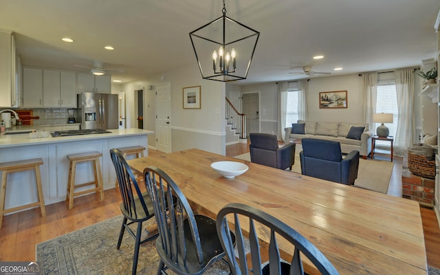 dining room with stairs, recessed lighting, wood finished floors, and ceiling fan with notable chandelier