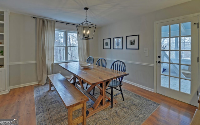 dining area featuring baseboards, an inviting chandelier, and wood finished floors