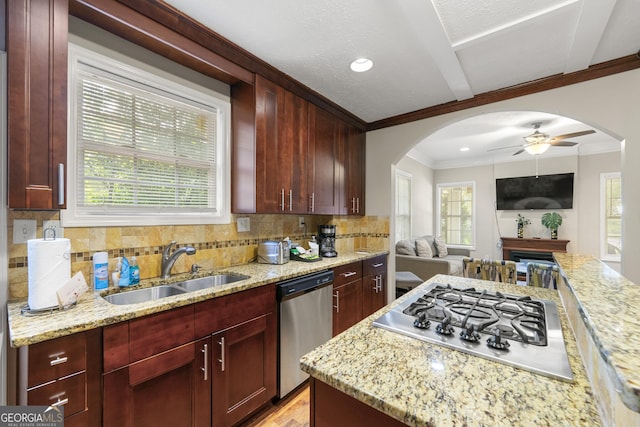 kitchen featuring arched walkways, stainless steel appliances, ornamental molding, a sink, and dark brown cabinets