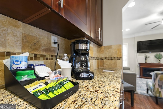 kitchen featuring tasteful backsplash, light stone counters, wood finished floors, a fireplace, and recessed lighting