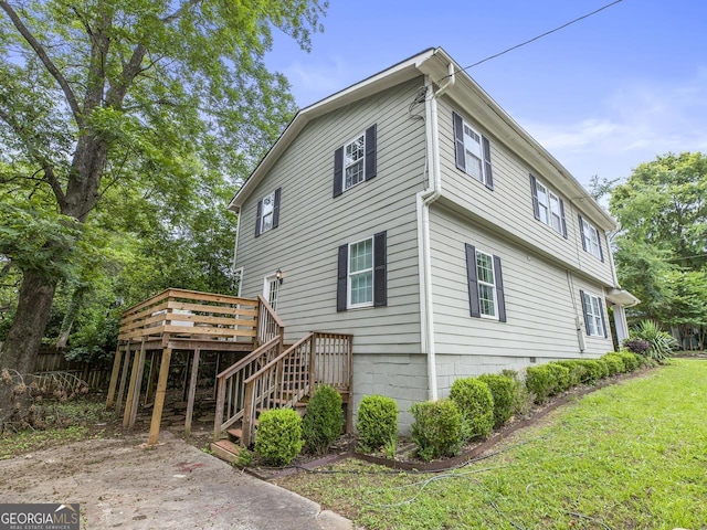 view of side of property with stairs, a lawn, and a wooden deck