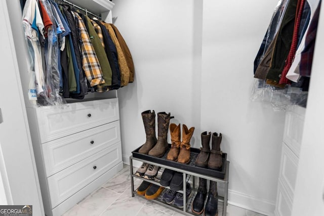 walk in closet featuring marble finish floor