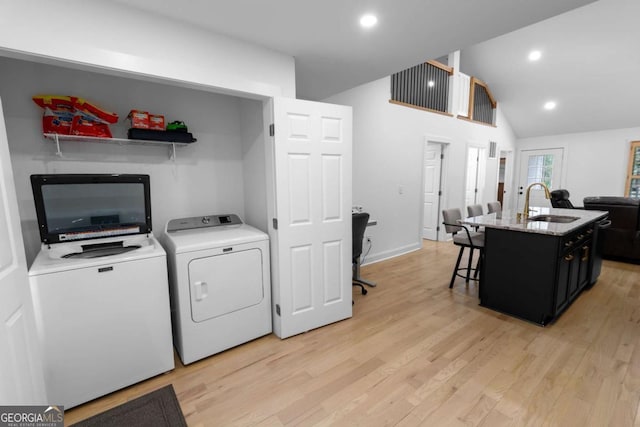 laundry room featuring laundry area, separate washer and dryer, a sink, and light wood finished floors