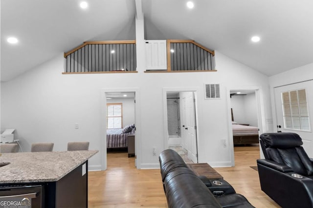 living room with light wood-style floors, visible vents, high vaulted ceiling, and baseboards