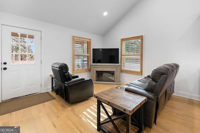 living area featuring recessed lighting, a glass covered fireplace, high vaulted ceiling, light wood-type flooring, and baseboards