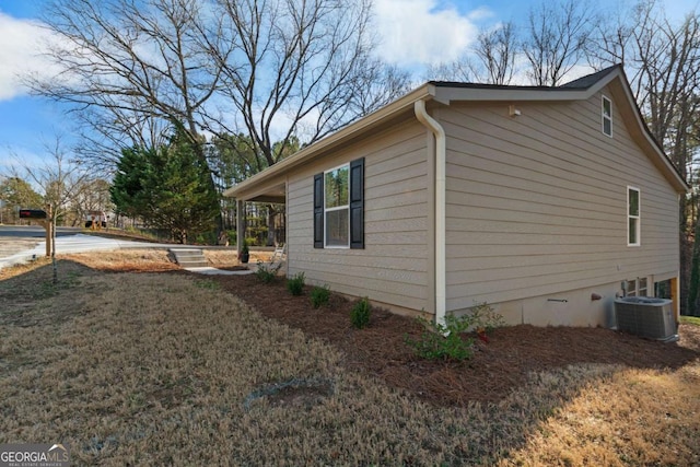 view of side of property with a lawn and central air condition unit