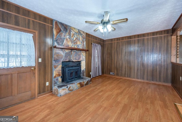 unfurnished living room featuring a textured ceiling, ceiling fan, wood walls, and wood finished floors