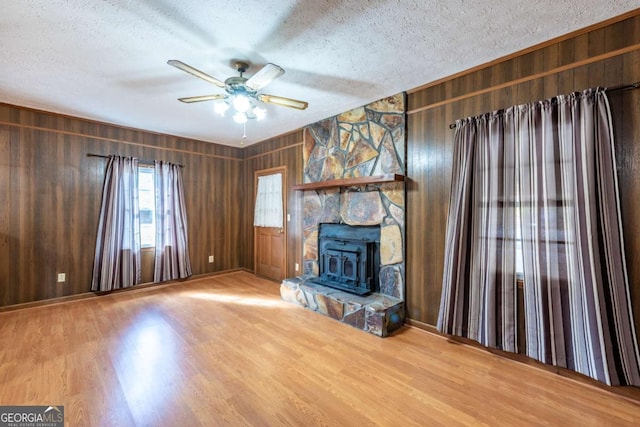 unfurnished living room featuring wood walls, ceiling fan, a textured ceiling, and wood finished floors