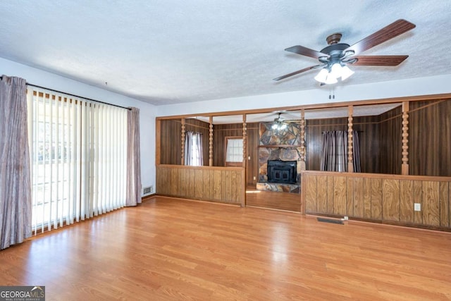 unfurnished living room with a textured ceiling, wood finished floors, visible vents, and a ceiling fan