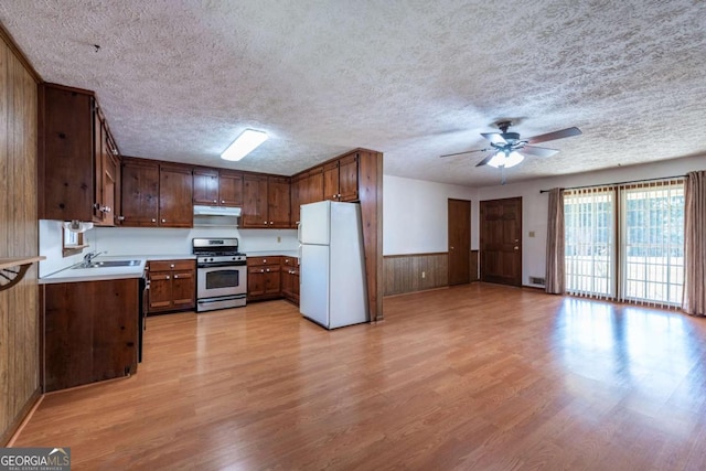 kitchen featuring stainless steel gas stove, light wood-style floors, light countertops, and freestanding refrigerator