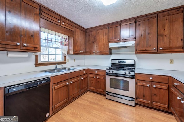 kitchen with black dishwasher, light wood-style floors, a sink, stainless steel gas range, and under cabinet range hood