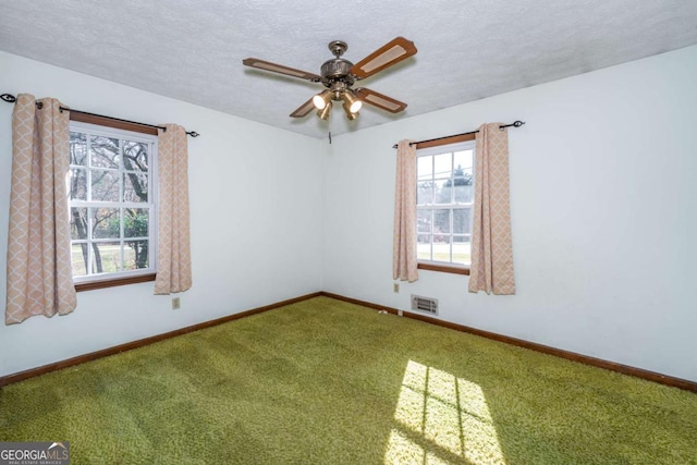 carpeted spare room featuring a textured ceiling, a ceiling fan, and baseboards