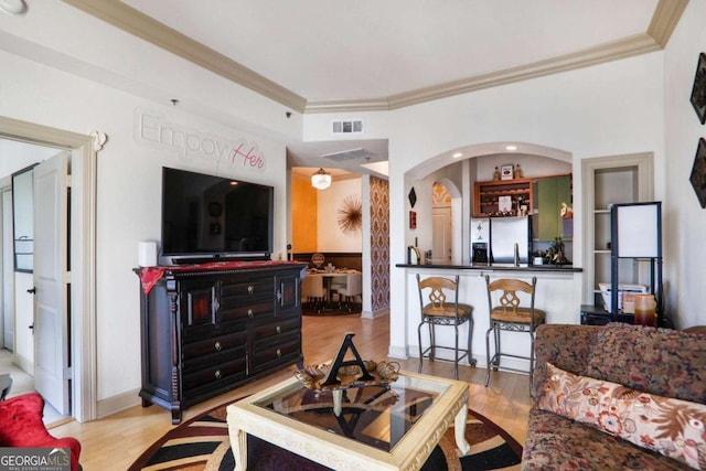 living room featuring light wood finished floors, visible vents, and ornamental molding