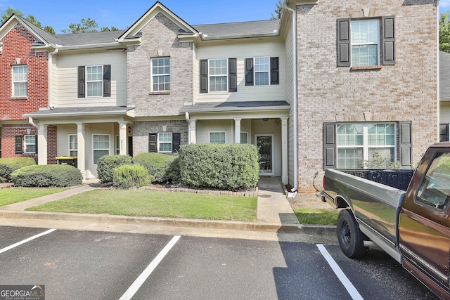 townhome / multi-family property with uncovered parking, a front lawn, and brick siding