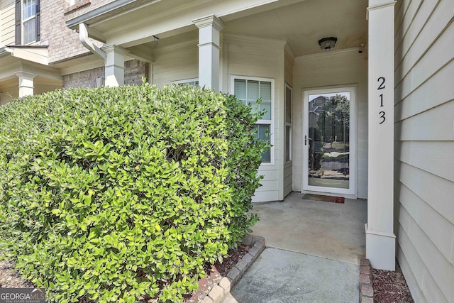 view of exterior entry featuring covered porch and brick siding