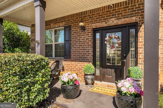 doorway to property with covered porch and brick siding