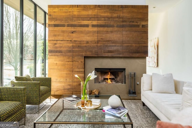 living room featuring a warm lit fireplace and plenty of natural light