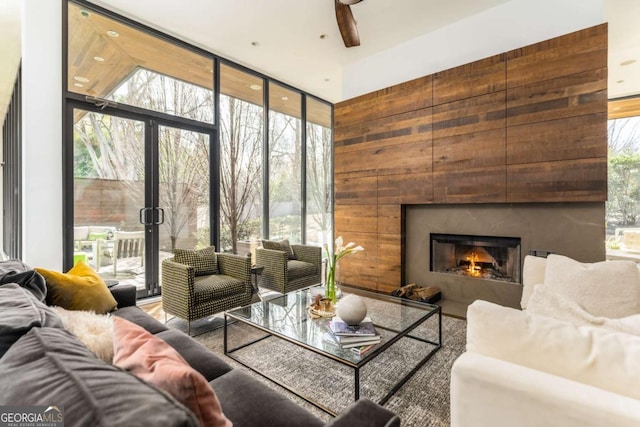 living area featuring a wall of windows, a ceiling fan, and a high end fireplace