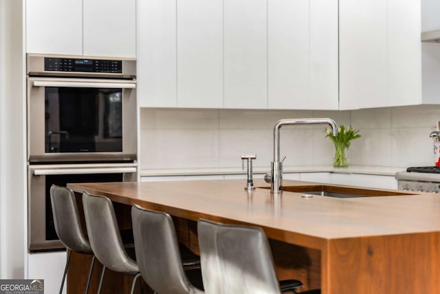 kitchen featuring stainless steel double oven, white cabinetry, and modern cabinets